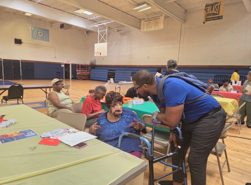 Dr. Jermaine Lee speaking with a senior participant during the wellness workshop